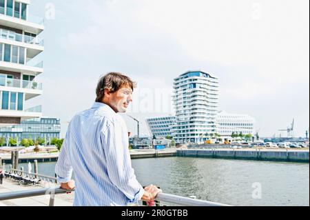 Homme adulte de taille moyenne regardant Strandkai, Marco-Polo-Tower en arrière-plan, HafenCity, Hambourg, Allemagne Banque D'Images