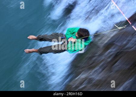 Un jeune homme ayant une pause après qu'il n'a pas réussi à s'équilibrer sur une ligne haute au-dessus d'un ruisseau, Fuessen, Bavière, Allemagne, Europe Banque D'Images