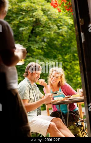 Jeune couple assis dans un café en plein air Banque D'Images