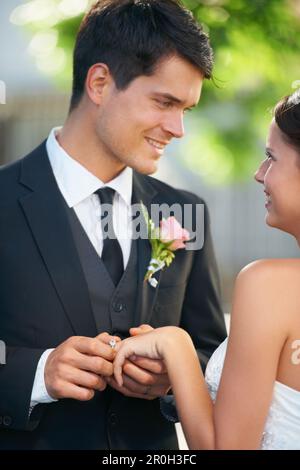 À long terme. Un jeune couple marié debout ensemble regardant l'un l'autre avec amour. Banque D'Images