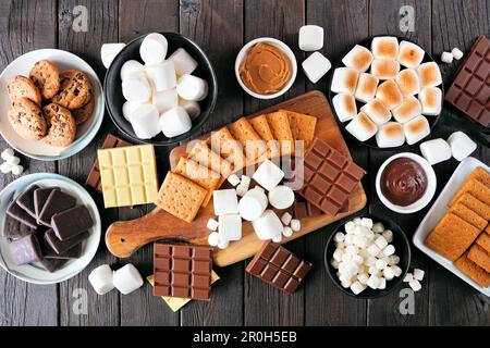 Table de buffet Smores. Marshmallows rôtis, craquelins, chocolat et une variété d'ingrédients. Vue en hauteur sur fond de bois sombre. Banque D'Images