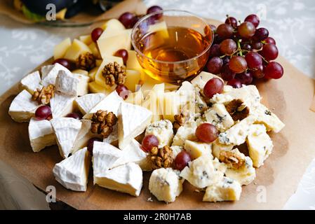 Assortiment de fromages et assiette de fruits. Une variété variée de fromages frais, fruits et noix présentés sur un grand plateau - un hors-d'œuvre sain idéal pour Banque D'Images