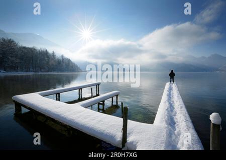 Homme debout sur la jetée couverte de neige au lac Kochel, Haute-Bavière, Allemagne Banque D'Images