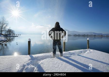 Homme debout sur la jetée couverte de neige au lac Kochel, Haute-Bavière, Allemagne Banque D'Images