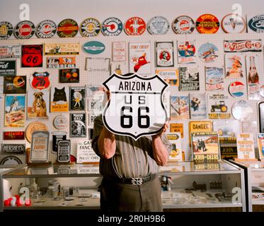États-Unis, Arizona, homme tenant signe Arizona US 66 dans un magasin d'enseigne, Holbrook Banque D'Images