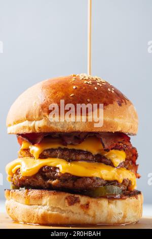 Hamburger. Double côtelette, double cheddar, bacon, oignons frits, cornichons, sauce et pain artisanal. Banque D'Images