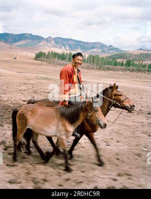 MONGOLIE, Parc national de Gorkhi-Terelj, un homme à cheval conduit un cheval à sa ferme et à sa maison Banque D'Images