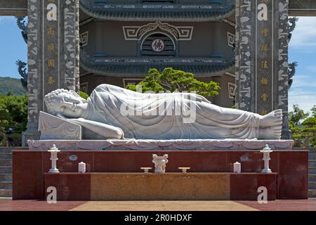 Statue en marbre blanc représentant le Bouddha couché au pied de la tour des reliques dans la pagode Linh Ung au sommet de la montagne son Tra. Banque D'Images