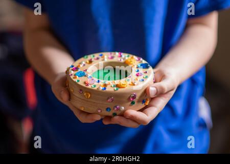 L'enfant économise de l'argent. Tirelire pour enfants décorée de strass dans les mains. Banque D'Images