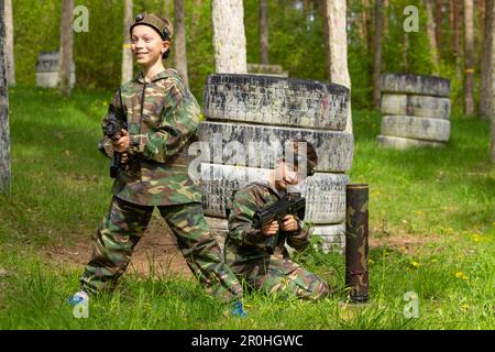 Deux garçons ont pleurés en camouflage jouant au laser tag dans un terrain de jeu spécial en forêt. Laser Tag est un jeu tactique militaire de commandement utilisant des armes laser sûres a Banque D'Images