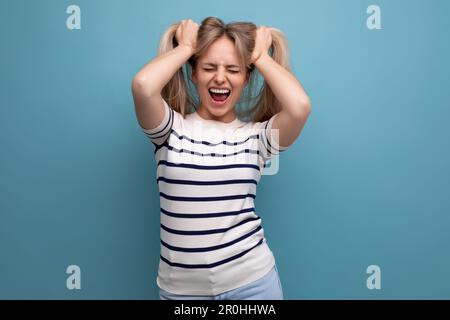 bonne femme blonde européenne bien entretenue avec des cheveux sains sur fond bleu isolé Banque D'Images