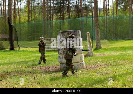 Deux garçons ont pleurés en camouflage jouant au laser tag dans un terrain de jeu spécial en forêt. Laser Tag est un jeu tactique militaire de commandement utilisant des armes laser sûres a Banque D'Images