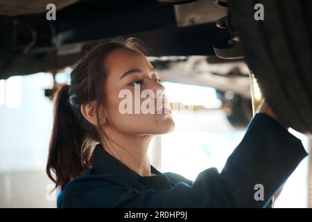 C'est le meilleur mécanicien automobile. une femme mécanicien travaillant sous une voiture soulevée. Banque D'Images