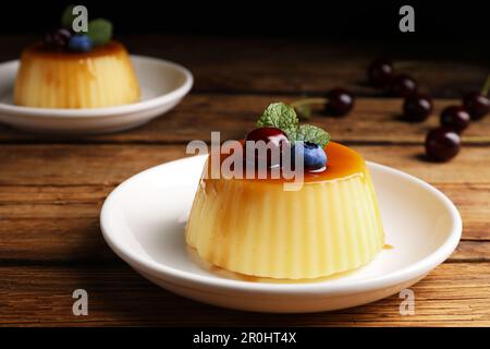 Assiette de délicieux pudding au caramel avec myrtille, cerise et menthe sur une table en bois Banque D'Images