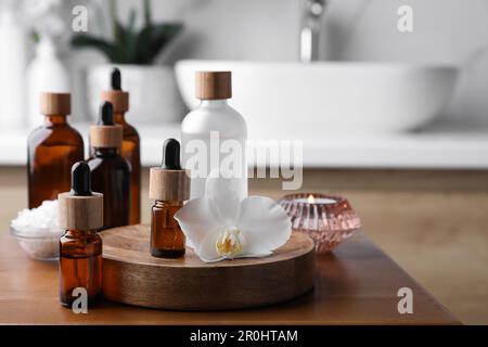 Huiles essentielles, fleurs d'orchidées et sel de mer sur une table en bois dans la salle de bains Banque D'Images