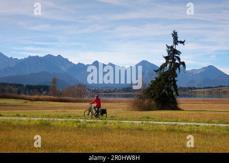 Biker, vue sur le lac d'aross Bannwaldsee aux Alpes d'Allgaeu, montagnes de Tannheim, Allgaeu, Bavière, Allemagne Banque D'Images