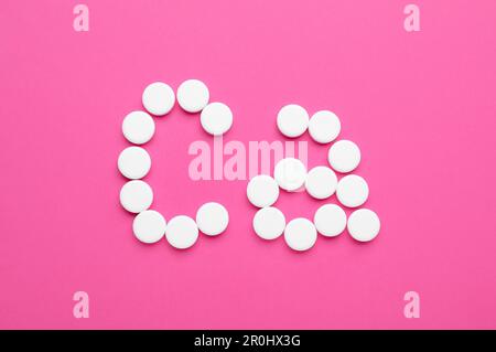 Symbole de calcium fait de pilules blanches sur fond rose, plat Banque D'Images