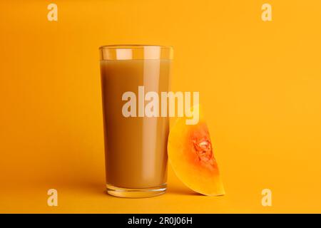 Délicieux jus de citrouille en verre et couper la citrouille sur fond orange Banque D'Images