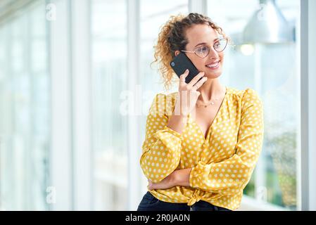 Chaque appel mène à un tout nouveau contrat. une jeune femme d'affaires utilisant un smartphone dans un bureau moderne. Banque D'Images