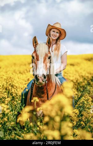 Une jeune femme blonde et son cheval haflinger appréciant leur temps au printemps dehors. Scène d'amitié entre une équestrienne et son poney Banque D'Images