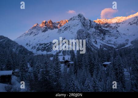 Maisons du village la Fouly en début de matinée, derrière les sommets du Mont Grepillon dans les premiers rayons du soleil, Val Ferret, Alpes Pennines, Canne Banque D'Images