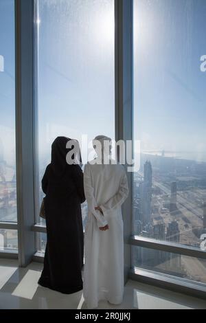 Homme et femme arabes vêtue de vêtements traditionnels Profitez de la vue depuis la terrasse d'observation Top au niveau 124 de la tour Burj Khalifa, Dubaï, Dubaï, AR Banque D'Images