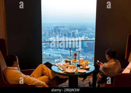 Client appréciant la vue sur Pékin, crépuscule, dîner, homme et femme, China World Trade Center Tower, restaurant au dernier étage, la plus grande gratte-ciel de Pékin Banque D'Images