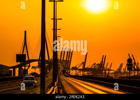 Le Koehlbrandbridge dans le port de Hambourg, entouré de grues à conteneurs pendant le coucher du soleil, Hambourg, Allemagne Banque D'Images