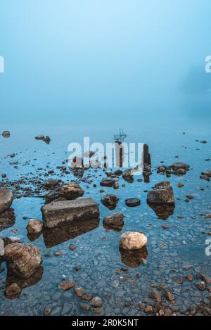 Rochers et pierres sur le lac Bohinj le matin brumeux, avec espace de copie Banque D'Images