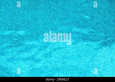 Carreaux de céramique bleue au fond de la piscine déformés par l'ondulation de l'eau comme arrière-plan Banque D'Images