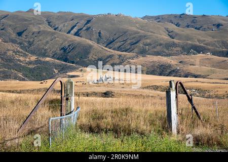 Porte avec lignes de chemin de fer, Central Otago Rail Trail, près de Middlemarch, Otago, South Island, Nouvelle-Zélande. Plage de roches et de piliers à distance. Banque D'Images