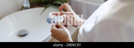 Gros plan du nettoyage de la brosse du visage dans les mains de la femme à l'évier dans la salle de bains. Outil de soin de la peau. Banque D'Images