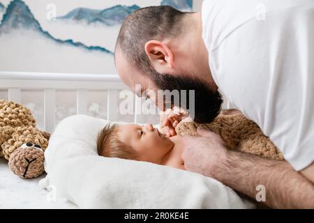 Le père se frottant le nez avec le nouveau-né dans le berceau à la maison. Banque D'Images