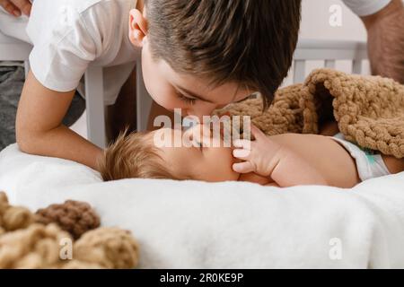 Grand frère aîné baiser nouveau-né, nouveau membre, bébé couché, portrait de famille de frères et sœurs amour gros plan Banque D'Images