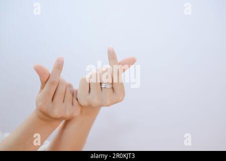 femelle de deux mains montrant un petit coeur sur un fond blanc isolé, gros plan mini coeur signe par les femmes main Banque D'Images