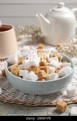 Différents cubes de sucre raffiné dans un bol sur une table rustique Banque D'Images