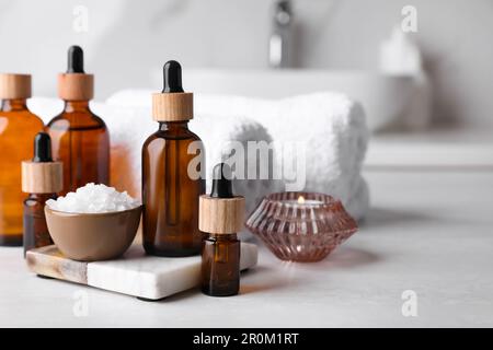 Huiles essentielles, sel de mer, bougie et serviettes sur comptoir blanc dans la salle de bains. Espace pour le texte Banque D'Images