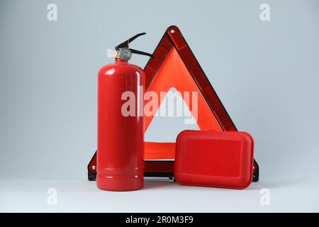 Triangle d'avertissement d'urgence, extincteur rouge et trousse de premiers soins sur fond gris clair. Sécurité automobile Banque D'Images