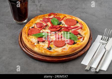 Pizza mélangée avec saucisse, salami et champignons sur une table en pierre Banque D'Images