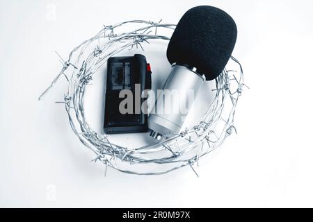 Microphone et dispositif d'enregistrement avec fil barbelé sur fond blanc Banque D'Images