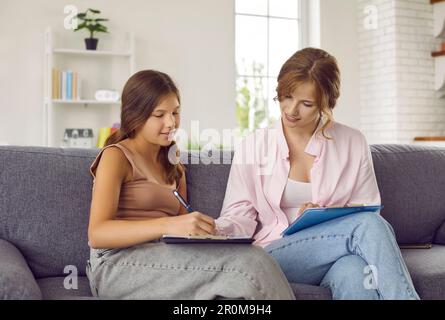 Jeune fille en séance de thérapie avec une jeune femme psychologue assise à côté d'elle sur le canapé. Banque D'Images