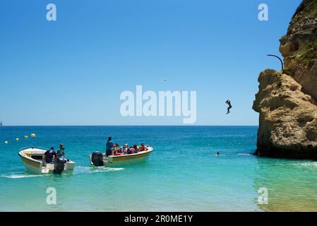 L'homme saute des rochers à la plage de Benagil, Algarve, Portugal Banque D'Images