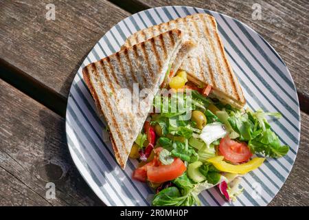 Sandwich au poulet grillé sur l'assiette avec salade d'accompagnement. délicieux repas santé sur la table de jardin Banque D'Images