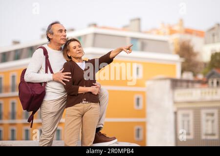 Couple de touristes senior pointant du doigt sur l'exploration de Lisbonne en vacances Banque D'Images