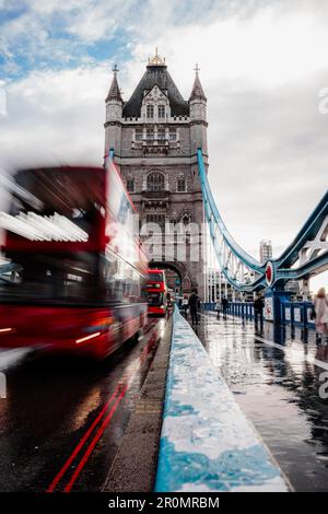 Un bus rouge à impériale vibrant passe sous un pont par un jour de rêve, avec des raindrops en cascade depuis le ciel Banque D'Images