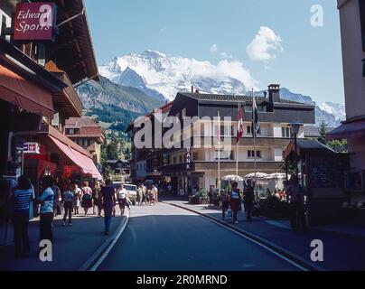 Vue sur la rue principale dans la station de Wengen dans la bernaise Overland avec la célèbre montagne Jungfrau à distance. Banque D'Images