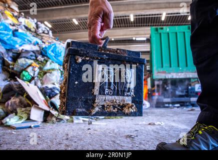 09 mai 2023, Mecklembourg-Poméranie occidentale, Rosenow: Une batterie automobile illégalement mise au rebut dans les déchets ménagers est triée par un employé de l'usine de tri de la société d'élimination des déchets REMONDIS Seenplatte à partir des déchets livrés par camion. Une mise au rebut incorrecte des batteries et accumulateurs provoque environ 30 incendies par jour en Allemagne, principalement dans les entreprises de mise au rebut des déchets. L'Association fédérale de l'industrie allemande de gestion des déchets (BDE), la société d'élimination des déchets OVVD et le district de Müritz présentent une campagne sous la devise "Focus: Battery" et informent sur les dangers de l'élimination Banque D'Images