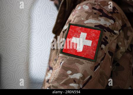 Suisse Soldat. Soldat avec le drapeau de la Suisse, drapeau de la Suisse sur un uniforme militaire. Vêtements de camouflage Banque D'Images