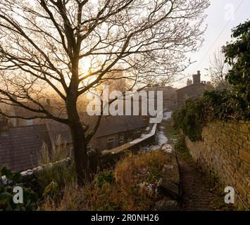 Un chemin pavé vers les maisons en terrasse dans une ville du nord. Un lever de soleil hiverne le matin à New Mills, Derbyshire qui surplombe les toits Banque D'Images