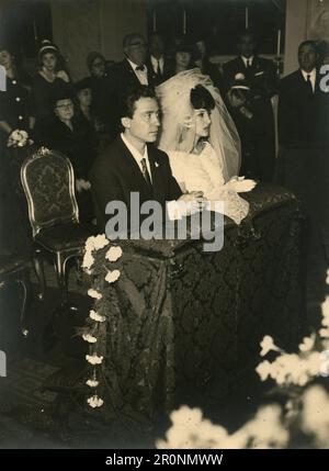 Mariée et marié dans l'église sur leurs genoux prêts à dire Oui, Italie 1960s Banque D'Images